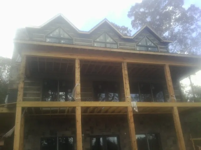 Dormers and porch framing on a large log home under construction — Roof Coating work by our crew in Miami