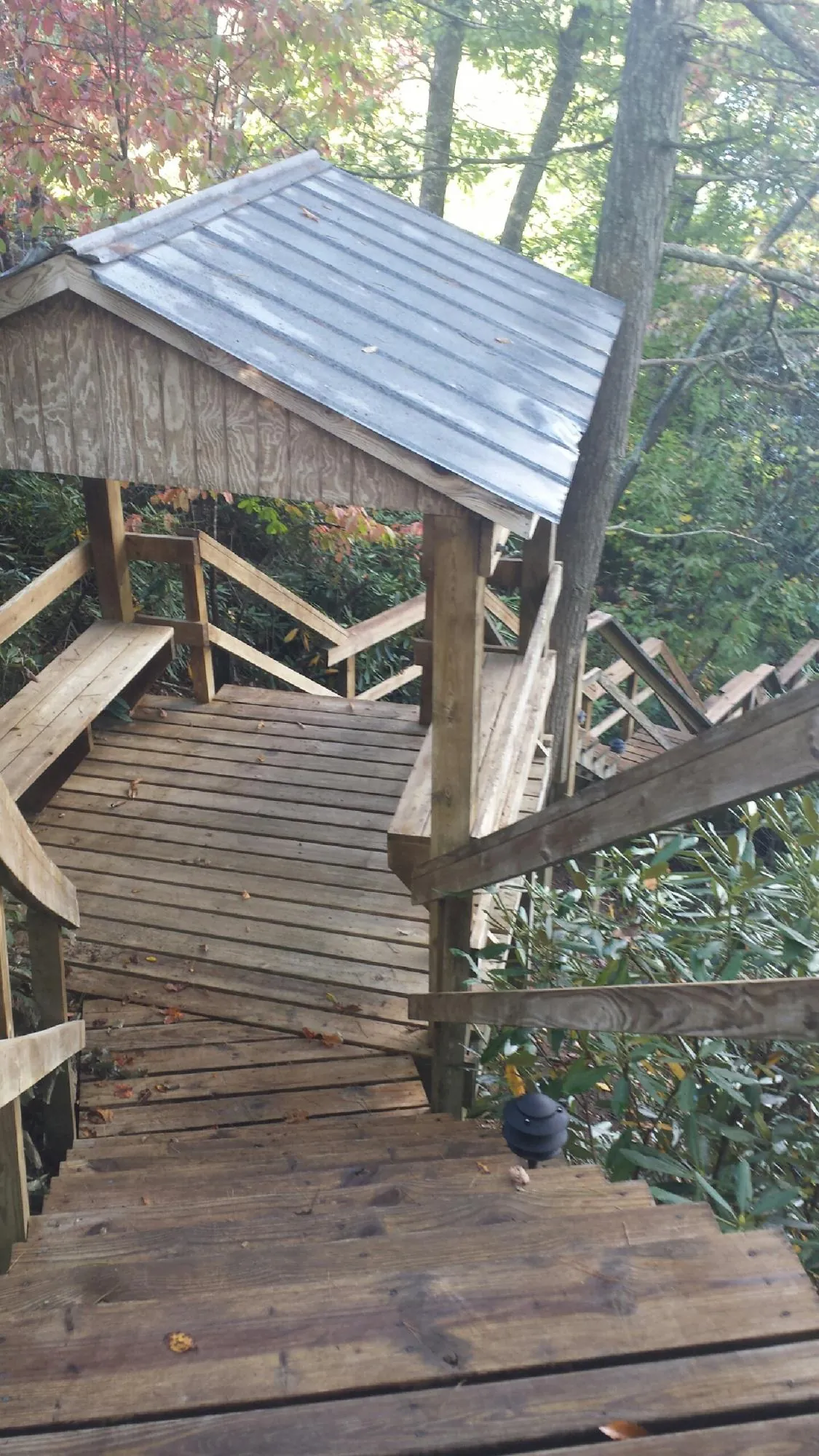 Metal roofed shelter over wooden steps on a wooded walkway — Skylight Repair & Installation work by our crew in Miami